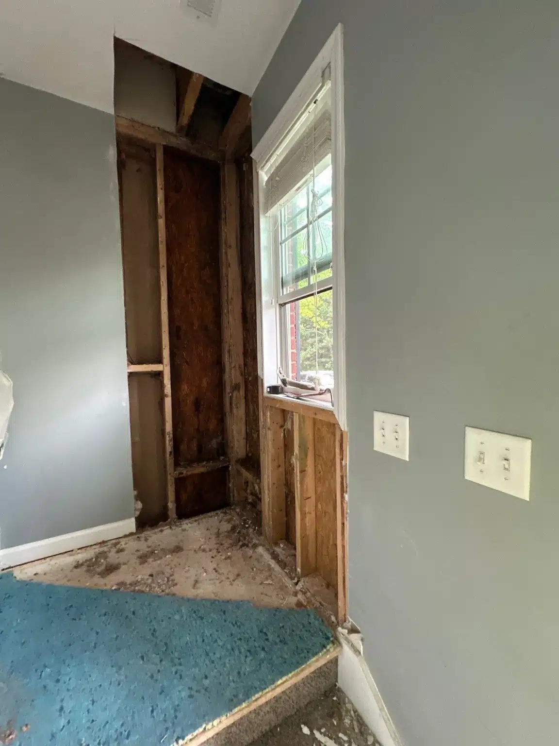 Entry door framing exposed beside the landing, with the affected material cut back