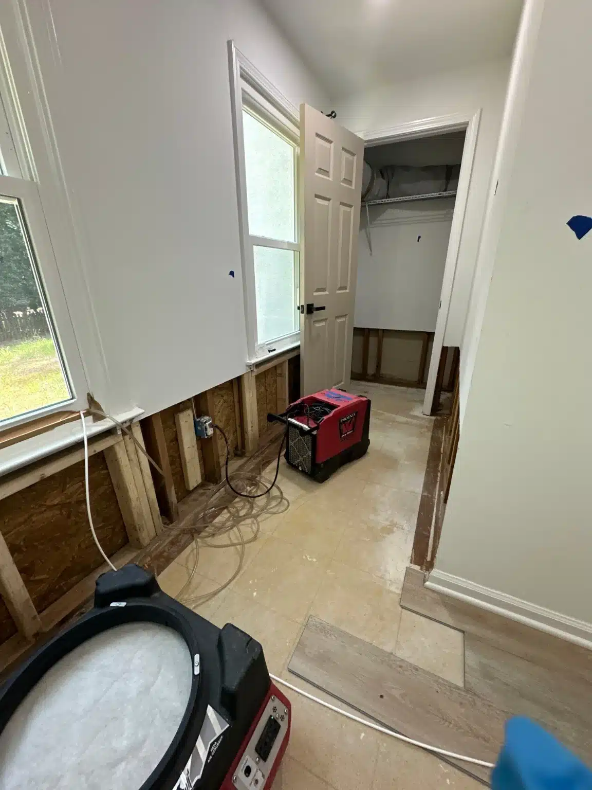 Basement room with the lower drywall flood cut away and drying equipment in place
