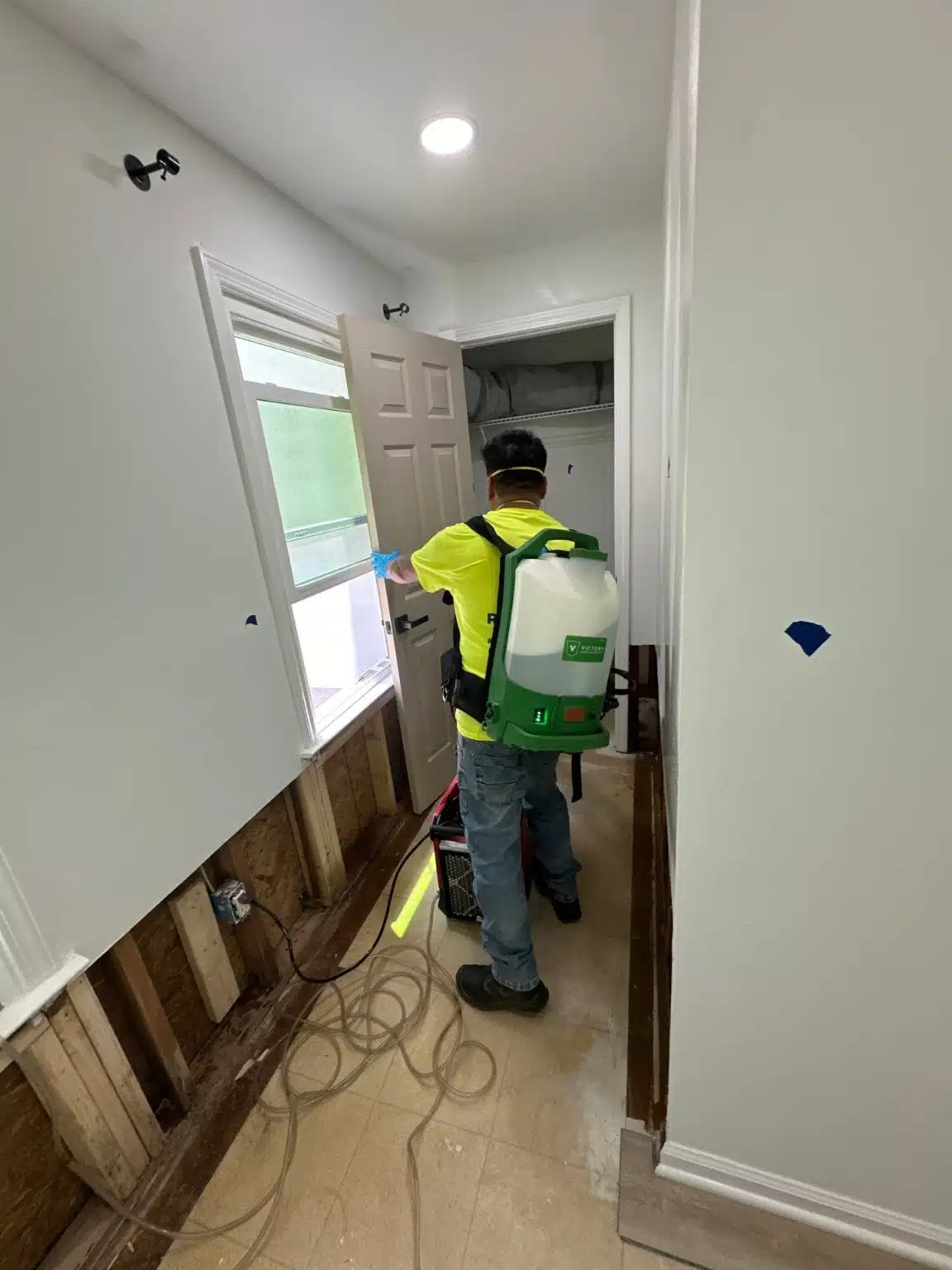 Technician working a hallway with the lower wall assemblies opened for drying