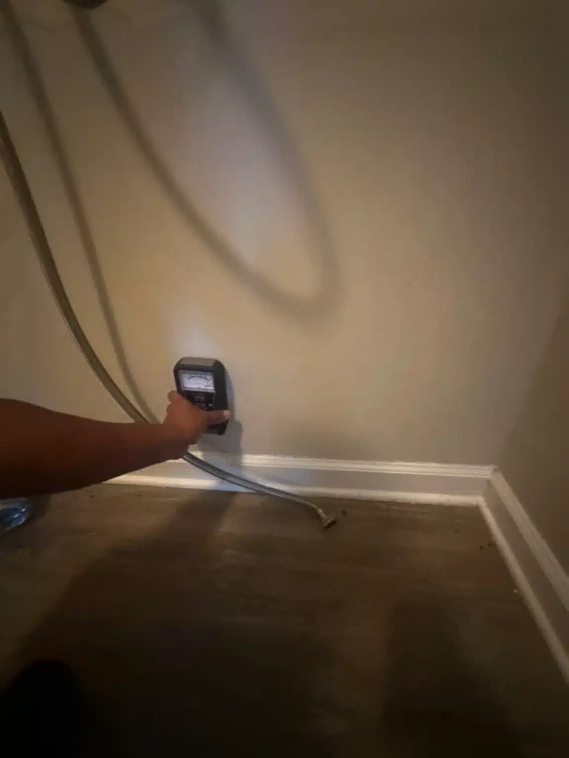 Pinless moisture meter reading taken on the wall above the baseboard to trace how far the water travelled
