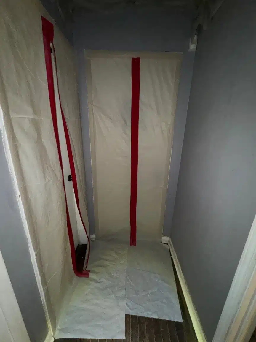 Sealed containment barrier taped across the hallway before any ceiling was opened