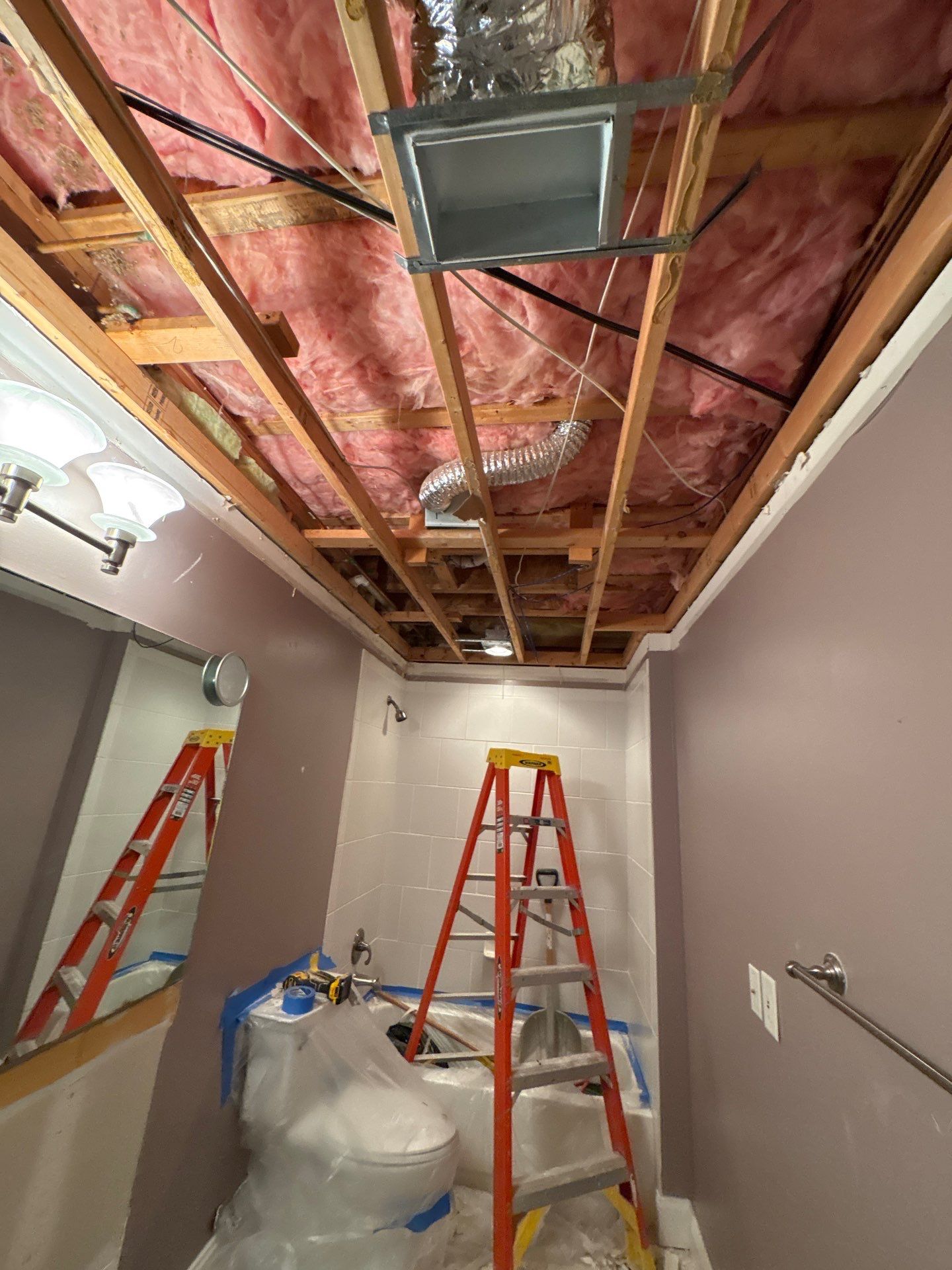 A ceiling opened up during a controlled tear-out, exposing joists and saturated insulation