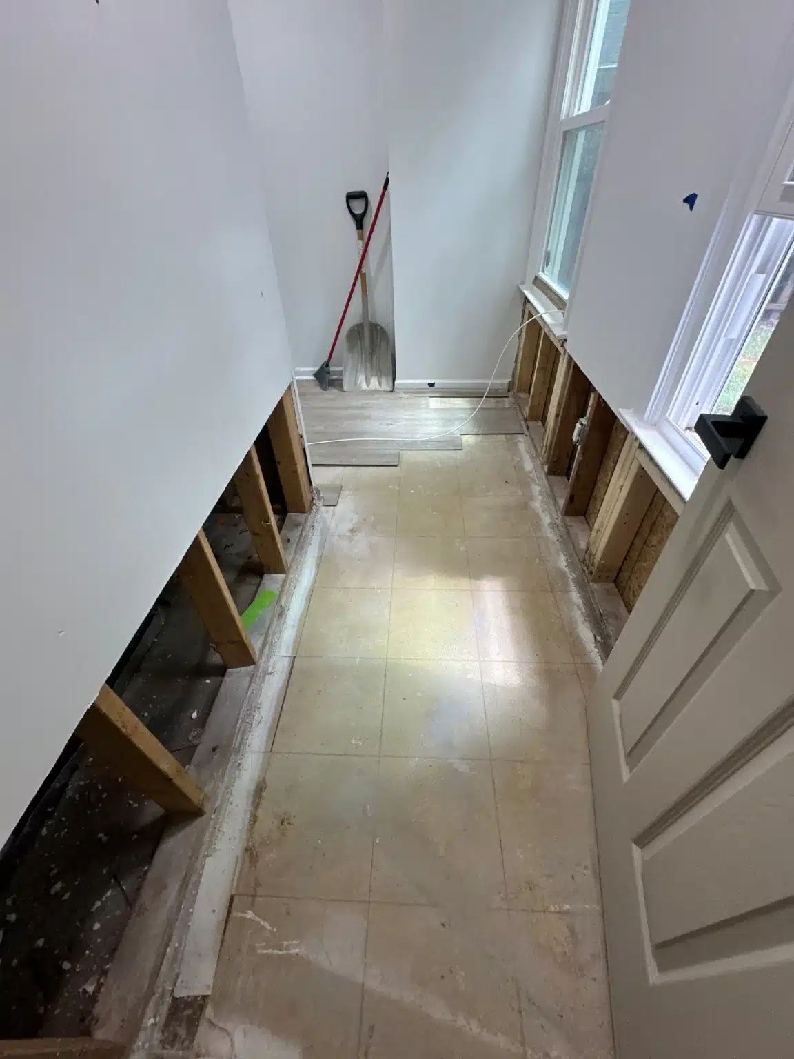 Basement hallway with baseboards and lower drywall removed along both walls