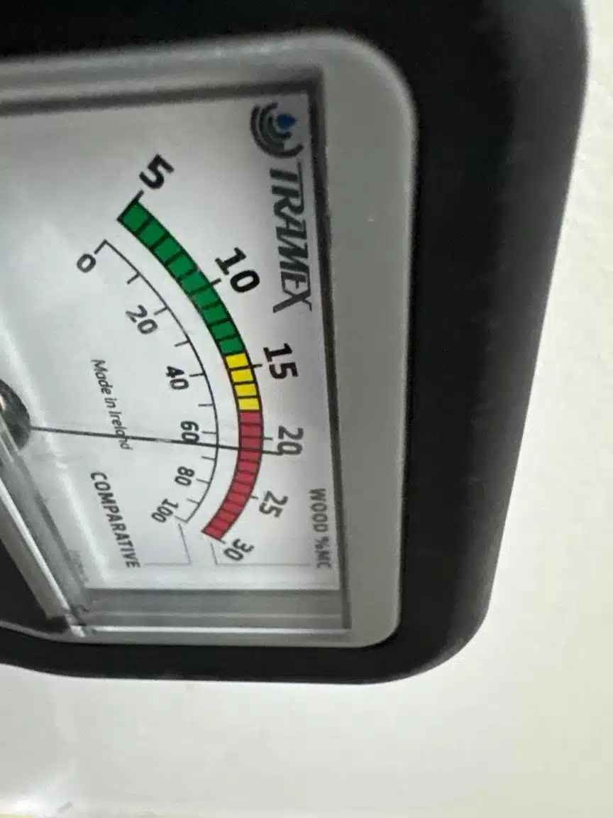 Moisture meter reading taken at the wall base to set the removal boundary