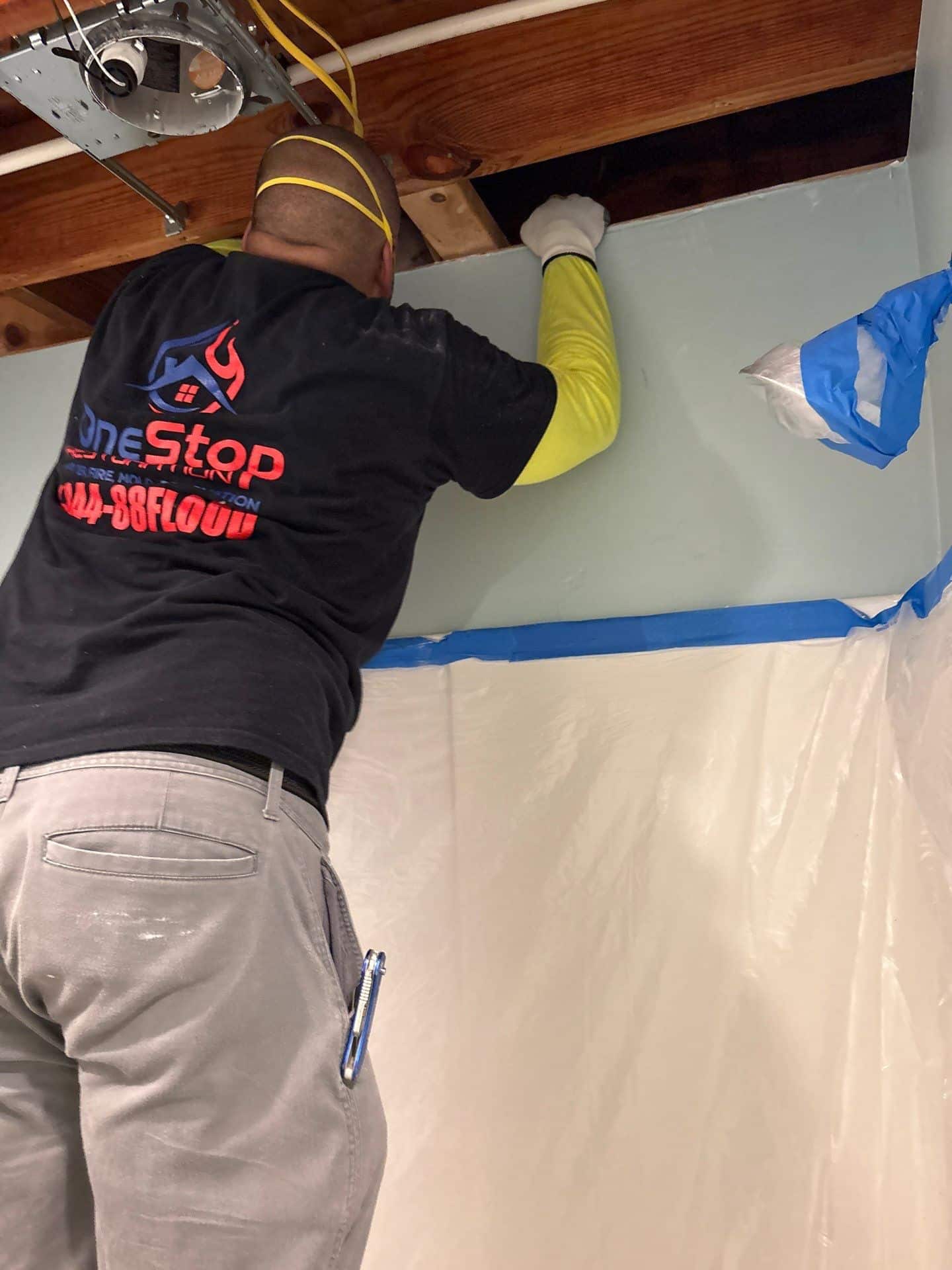 A One Stop Restoration technician sealing plastic containment sheeting over a doorway on an Atlanta job site