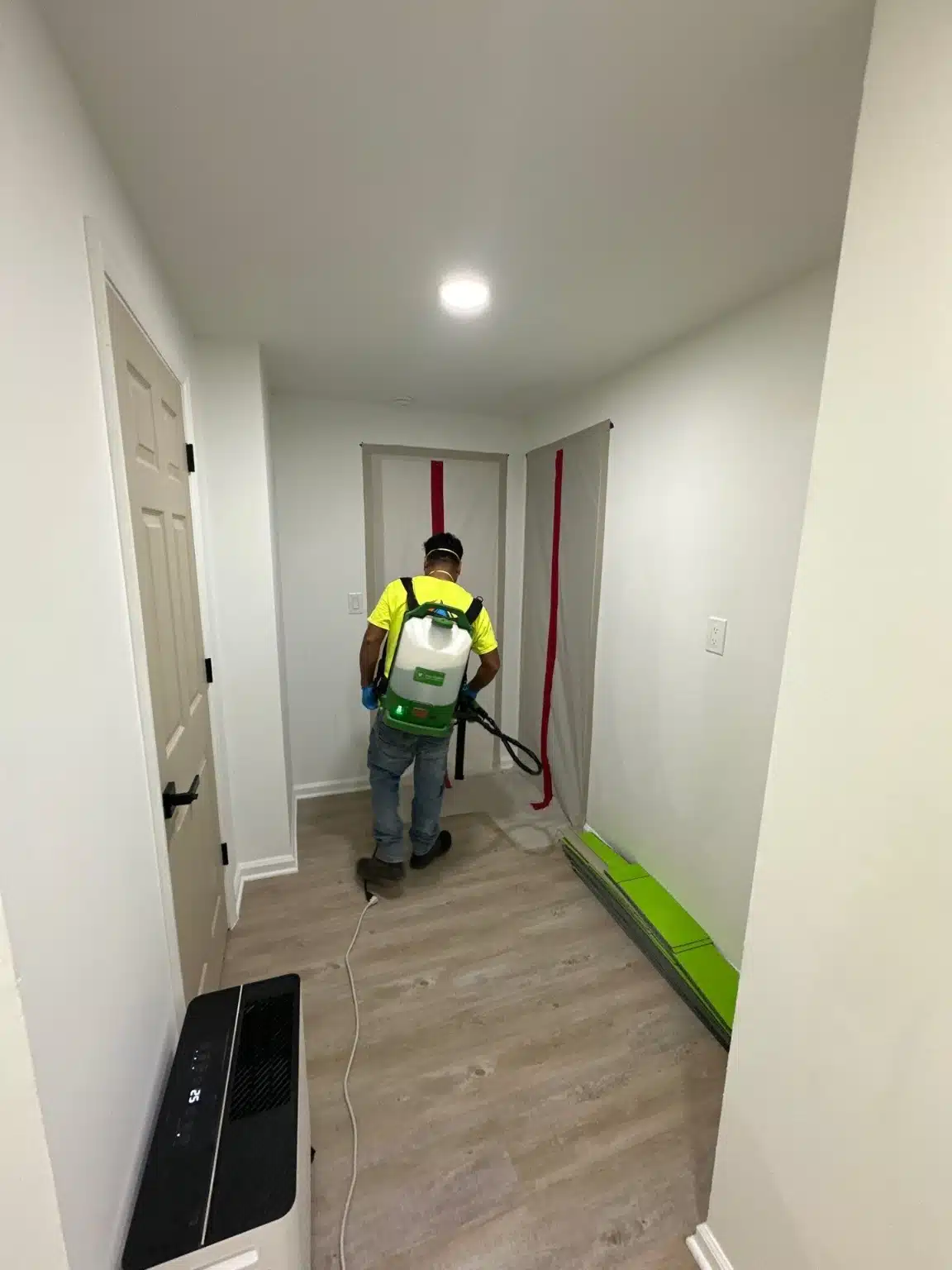 A One Stop Restoration technician working a hallway, with containment set up at the far end