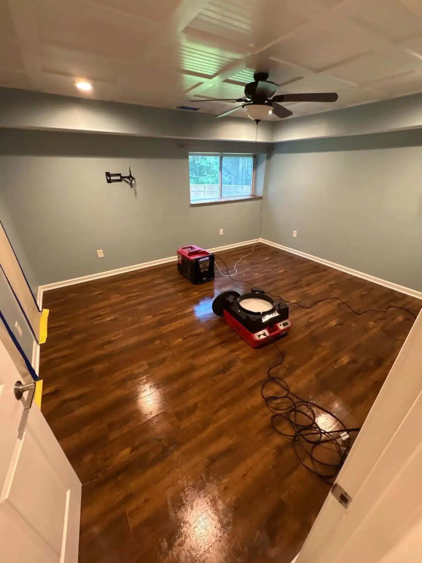 Wet hardwood floor with air movers and a dehumidifier drying the room