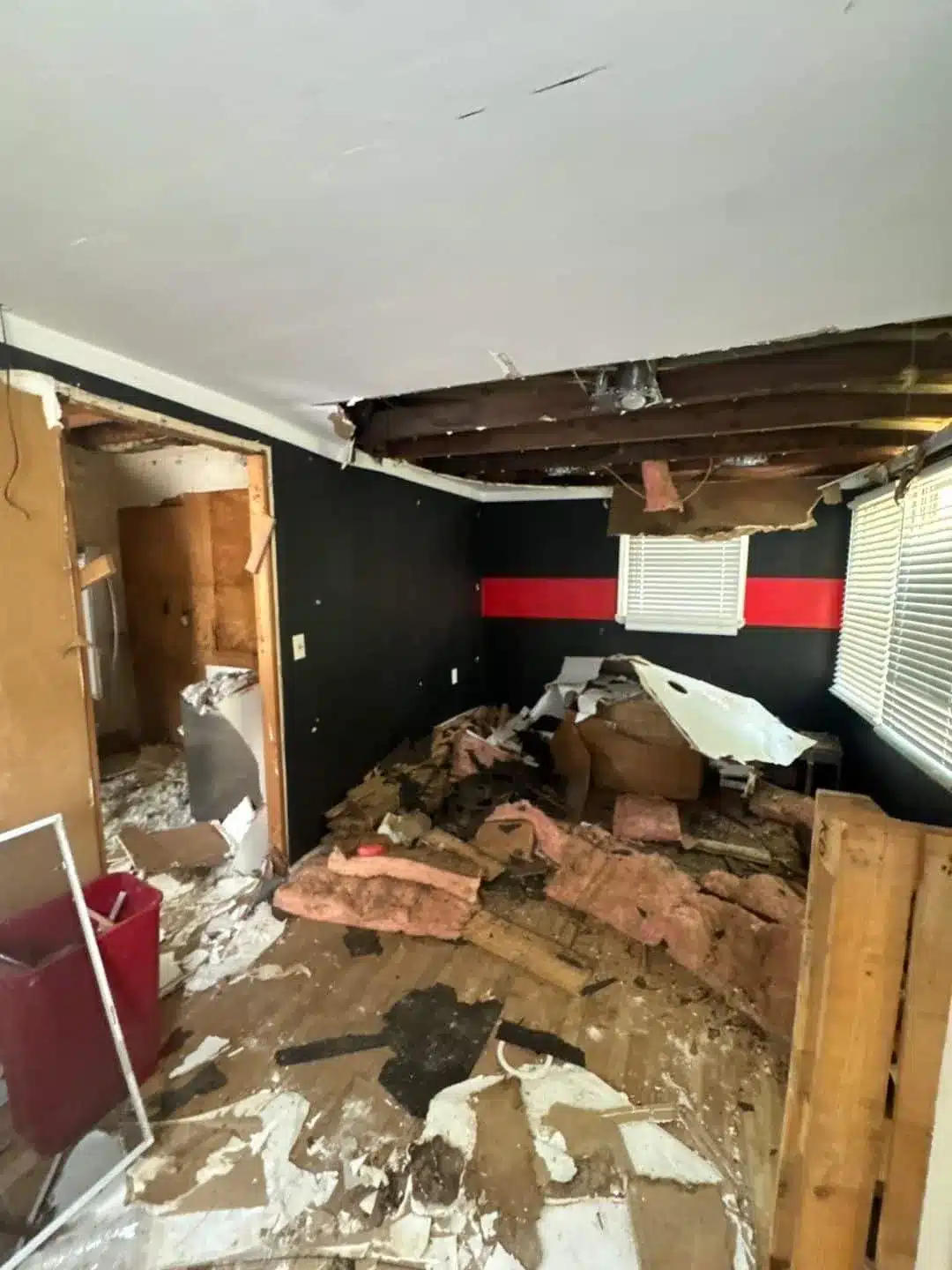 Extensive ceiling opening and scattered drywall debris awaiting cleanup and rebuilding
